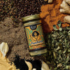 Jar of 'Manteria' seasoning blend surrounded by spices and herbs on a textured surface